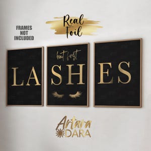 May include: Three black framed prints with gold lettering and accents. The prints read "but first lashes" with a pair of eyelashes in the middle print. The text is in a gold foil finish.