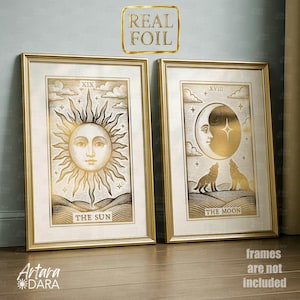 May include: Two framed gold foil prints. One depicts a sun with the text "THE SUN" and the Roman numeral "XIX". The other shows a moon with the text "THE MOON" and the Roman numeral "XVIII". The prints are in gold frames.
