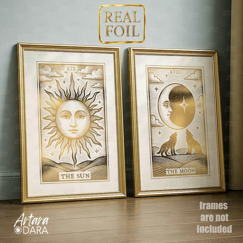May include: Two framed gold foil prints. One depicts a sun with the text "THE SUN" and the Roman numeral "XIX". The other shows a moon with the text "THE MOON" and the Roman numeral "XVIII". The prints are in gold frames.