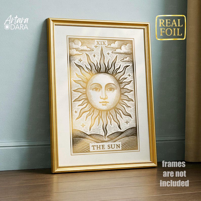 May include: A framed gold foil print of The Sun tarot card. The artwork features a detailed illustration of a sun with a face, surrounded by rays, clouds, and the text "THE SUN". The frame is gold.