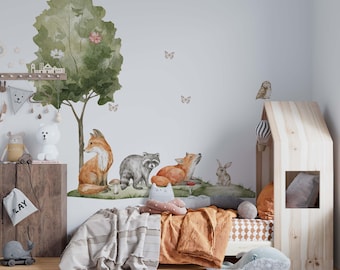 May include: A wall decal set featuring a large green watercolor tree, a fox, a raccoon, a rabbit, and butterflies. The design includes woodland animals in natural tones applied to a plain wall above a wooden bed frame and a round patterned rug.