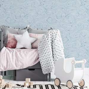 May include: A light blue and white patterned wallpaper with a white knitted throw blanket and a white toy stroller on a gray bed with pink bedding and a white star pillow.
