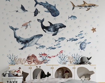 May include: A wall decal set featuring watercolor illustrations of various marine life including a whale, sharks, dolphins, sea turtles, an octopus, and small fish, all surrounded by light blue bubbles and starfish on a plain white background.