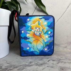 May include: A square zippered pouch featuring a vibrant illustration of a yellow star-shaped creature with teal accents, surrounded by a blue starry sky and clouds. The pouch has a black fabric wrist strap attached with a small red metal carabiner.