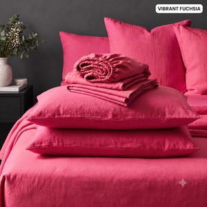 May include: A vibrant fuchsia bedding set featuring a flat sheet, two stacked pillows, and a folded fitted sheet with elastic edges. The fabric has a visible woven texture, and the set is displayed in a monochromatic arrangement with matching pillowcases.