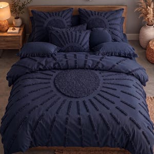 May include: A navy blue bedding set featuring a central circular tufted design with radiating tufted lines. The set includes a duvet cover, two large square shams, two rectangular shams with fringe edges, and a round pillow, all in navy blue.