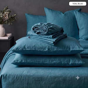 May include: A teal blue bedding set featuring a flat sheet, a fitted sheet, and two pillowcases. The fabric has a visible woven texture. A label in the upper right corner displays the text TEAL BLUE. The items are arranged in a stack.