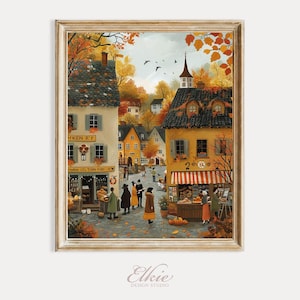 May include: A framed print of a European village scene in autumn. The artwork depicts buildings with orange and yellow hues, people, and a church steeple. The print has a gold-colored frame and the artist's signature at the bottom.