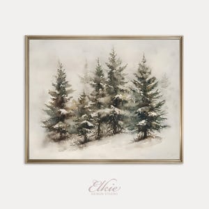 Puede incluir: Pintura a la acuarela de una escena de bosque invernal con árboles de hoja perenne cubiertos de nieve. La obra de arte está enmarcada en un marco dorado. La pintura tiene una paleta de colores suaves y apagados con una calidad de ensueño. La firma del artista, "Elkie Design Studio", está en la parte inferior.
