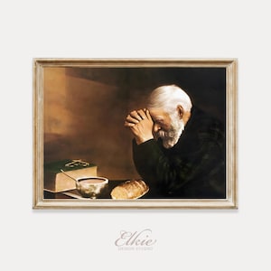 Op de afbeelding: Een ingelijste prent van een oude man met een witte baard, biddend. Een bijbel, een kom en een brood liggen op tafel. De prent heeft een warm, sepia-getinte kleurenpalet.