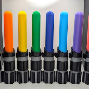 K&ouml;nnte beinhalten: Eine Sammlung von acht farbigen Lichtschwertern mit unterschiedlich farbigen Klingen: rot, orange, gelb, gr&uuml;n, blau, hellblau, lila und pink. Die Griffe sind schwarz und grau.