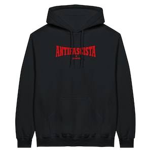 Può includere: Felpa con cappuccio nera con tasca a marsupio frontale. Il testo rosso "ANTIFASCISTA" è arcuato sul petto, con "SIEMPRE" sotto. La felpa ha un cordino e un cappuccio.
