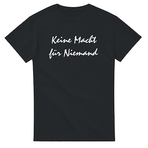 May include: Black t-shirt with white text that reads "Keine Macht für Niemand".