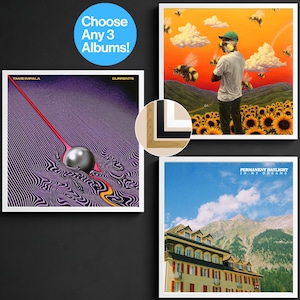 Può includere: Tre stampe artistiche di album incorniciate su un muro nero. Una presenta un design rosso e argento, un'altra mostra una persona in un campo di girasoli e la terza raffigura una scena di montagna. Un cerchio blu recita "Scegli 3 album!"