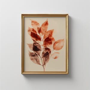 May include: A framed botanical print featuring a cluster of reddish-brown leaves against a cream background. The leaves have a watercolor effect, with varying shades of brown and red. The frame is gold-colored, adding a touch of elegance to the artwork.