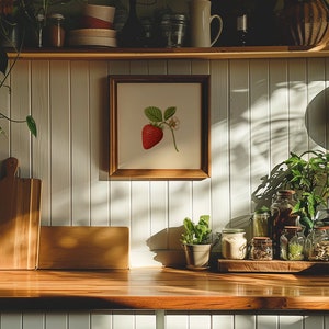 May include: A wooden shelf with a framed print of a red strawberry on a white background. The shelf is decorated with plants, jars, and other kitchen items.
