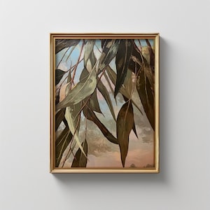 May include: A framed painting depicting eucalyptus leaves in varying shades of green and brown, set against a soft, pastel sky. The artwork is presented within a gold-coloured frame, enhancing the botanical theme.