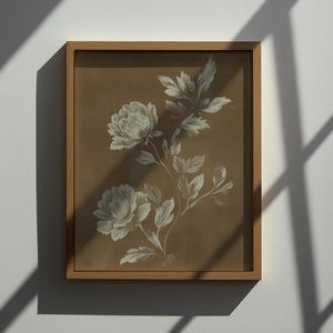 以下が含まれることがあります： 茶色の背景に白い牡丹の花と葉が描かれた、額装された植物画。 アートワークは明るい茶色の木製フレームに収められており、クラシックでエレガントな美しさです。 白い壁にプリントが飾られています。