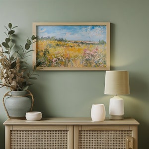 May include: A wooden cabinet with two doors and a woven rattan design. The cabinet is decorated with a framed landscape painting and a white table lamp with a beige lampshade.