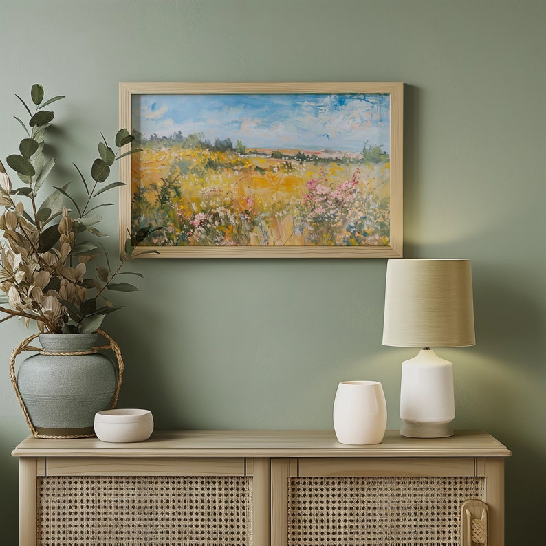 May include: A wooden cabinet with two doors and a woven rattan design. The cabinet is decorated with a framed landscape painting and a white table lamp with a beige lampshade.