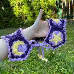 May include: A purple and yellow crocheted collar with a star and crescent moon design.
