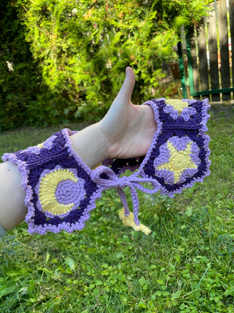 May include: A purple and yellow crocheted collar with a star and crescent moon design.