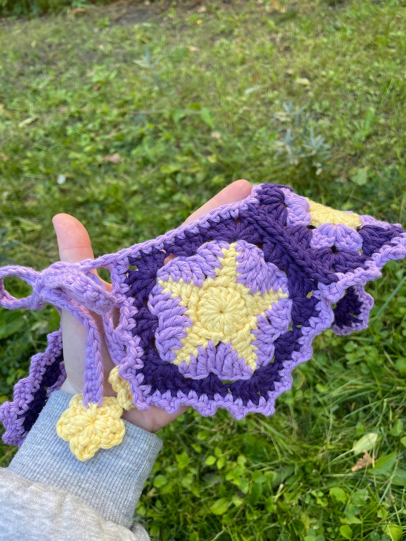 May include: A crocheted purple and yellow star-shaped garland with a yellow flower accent.
