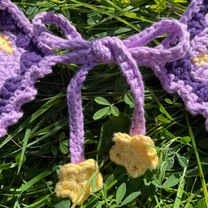 May include: Purple and yellow crocheted garland with a bow and star-shaped accents.