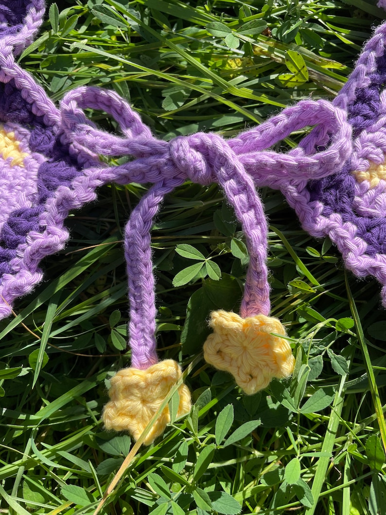 May include: Purple and yellow crocheted garland with a bow and star-shaped accents.