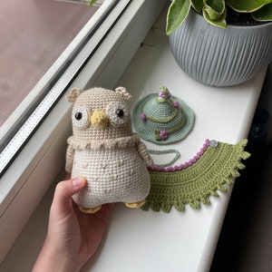 May include: A crocheted owl with brown and white yarn, a green crocheted hat with pink flowers, and a green crocheted collar with pink trim.