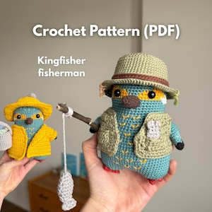 Op de afbeelding: Twee gehaakte ijsvogelvogelfiguren. Eén vogel draagt een gele hoed en jas en houdt een mand vast. De andere vogel draagt een hoed en vest en houdt een hengel met een vis vast. De tekst "Crochet Pattern (PDF)" en "Kingfisher fisherman" zijn zichtbaar.