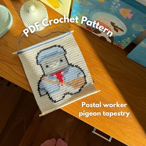 May include: A handmade crochet tapestry featuring a postal worker pigeon design. The tapestry is cream-colored with a blue hat and uniform, a red tie, and a black outline. The text "PDF Crochet Pattern" and "Postal worker pigeon tapestry" are visible.