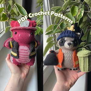 May include: Two crocheted stuffed animals, a red dragon wearing a firefighter hat and a gray raccoon wearing a blue hat and holding a green trash can.