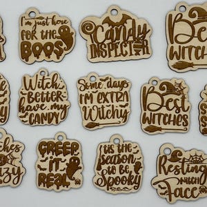 May include: Twelve wooden Halloween-themed ornaments with various sayings, including "Black Cats Only", "I'm Just Here For The Boo's", "Candy Inspector", "Best Witches", "Cute And Creepy", "Witch Better Have My Candy", "Some Days I'm Extra Witchy", "Best Witches", "Spooky Season", "Witches Be Crazy", "Creep It Real", "Tis The Season To Be Spooky", and "Resting Witch Face".