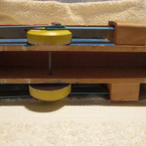 May include: A wooden toy train with yellow wheels and a blue body. The train has two levels and is made of wood.