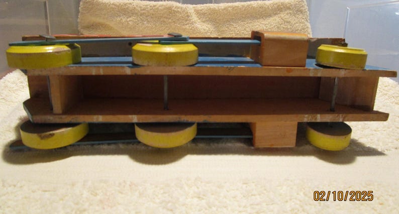 May include: A wooden toy train with yellow wheels and a blue body. The train has two levels and is made of wood.