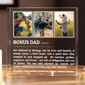 May include: A clear acrylic block with the words "BONUS DAD" and a definition, accompanied by three family photos. A lit white candle and string lights are on a small table.