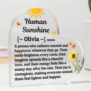 May include: A heart-shaped acrylic plaque with the words "Human Sunshine" and a definition. The design includes a yellow sun, hearts, and a sunflower illustration. The text defines a person who radiates warmth and happiness.