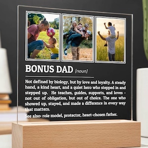 May include: A clear acrylic plaque with the words "BONUS DAD" and three family photos. The plaque sits on a rectangular wooden base. The text below describes the role of a bonus dad.