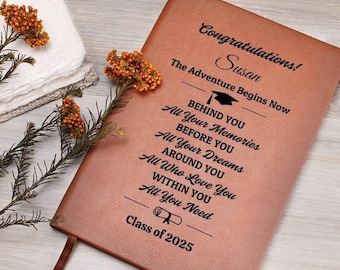 May include: A brown leather journal with the text "Congratulations! Susan, The Adventure Begins Now" and other inspirational text. The journal includes a ribbon bookmark and the words "Class of 2025".