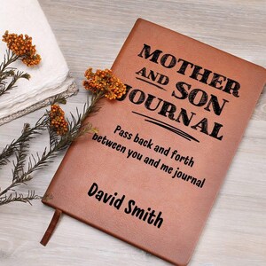 May include: Brown leather journal with the text "Mother and Son Journal" and "Pass back and forth between you and me journal". The name "David Smith" is personalized on the bottom of the journal.