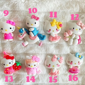 May include: Set of 10 Hello Kitty charms, featuring Hello Kitty in various poses and outfits, including riding a unicorn, holding flowers, and wearing a party hat. The charms are made of plastic and are approximately 2.5 cm in size.