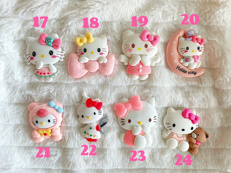 May include: A set of 10 Hello Kitty charms, each featuring a different design. The charms are made of pink, white and yellow plastic and are approximately 5 cm tall. The charms are numbered 17 through 24.