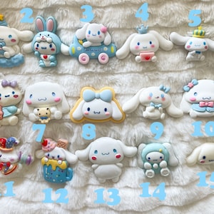 May include: Fifteen colorful, handmade, ceramic figurines of a cartoon dog character. The figurines are all different designs and feature various colors, including blue, pink, yellow, and white.