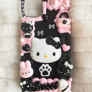 May include: Black and pink phone case featuring Hello Kitty, a bunny, a cat, and a paw print. The case has a pink and white bow, a pink purse, and the word "Sweet" written on it.