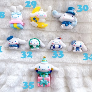 May include: A collection of ten small, white, ceramic figurines of a cartoon dog wearing different outfits. The dog is wearing a blue hat, a green dress, a blue and white striped life preserver, a blue bow, a blue hat with a white top hat, a yellow crescent moon, a pink and blue gift box, a green and white Christmas tree hat, and a pink and blue gift box with a green and white Christmas tree hat.