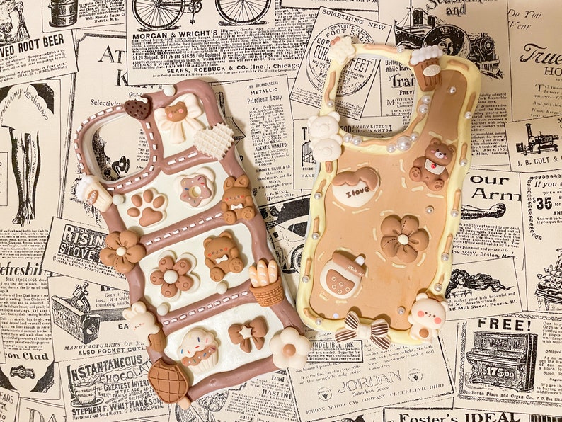 May include: Two phone cases decorated with brown, white, and beige 3D clay embellishments. The embellishments include bears, flowers, bows, and other cute designs. One case has the text "I love" on it.