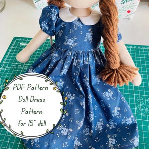 May include: A handmade doll wearing a blue floral print dress with a white collar. The doll has long brown yarn braids. The image includes text that reads "PDF Pattern Doll Dress Pattern for 15" doll".