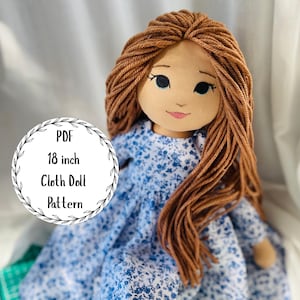 Può includere: Una bambola di stoffa fatta a mano con capelli di filo marrone e un vestito floreale blu. La bambola ha un viso dipinto con occhi neri e bocca rosa. L'immagine include una grafica circolare con il testo "PDF 18 inch Cloth Doll Pattern".