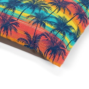 May include: A colorful pillow with a repeating pattern of palm trees silhouetted against a sunset background. The colors in the sunset are orange, yellow, blue, and green.